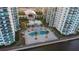 Overhead shot of a community pool surrounded by tall condo buildings, palm trees, and lounge chairs at 231 Riverside Dr # 708, Daytona Beach, FL 32117