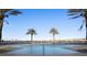 A lovely pool surrounded by palm trees with a stunning view of the water and bridge in the distance at 231 Riverside Dr # 708, Daytona Beach, FL 32117