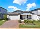 Charming single Gathering home featuring a brick driveway, two-car garage, and a cozy front porch at 2311 Bear Peak Road, Minneola, FL 34715