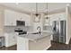 Modern kitchen featuring white cabinets, stainless steel appliances, and stylish pendant lighting at 2311 Bear Peak Road, Minneola, FL 34715
