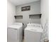 Functional laundry room featuring white washer and dryer units, shelving, and gray walls at 233 Primrose Dr, Davenport, FL 33837