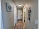 Hallway view with neutral walls, art, tile flooring, and a door at the end of the hall at 2480 Alamanda Ave, Deltona, FL 32738