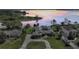 Lakefront estate with manicured grounds, circular driveway, and breathtaking water views at sunset at 29150 Beauclaire Dr, Tavares, FL 32778