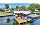 Aerial view of a boat dock and boat lift next to a landscaped yard, and surrounding houses and waterways at 29150 Beauclaire Dr, Tavares, FL 32778