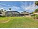 Expansive backyard featuring a large screened-in pool enclosure with a patio, lush greenery, and privacy landscaping at 29150 Beauclaire Dr, Tavares, FL 32778