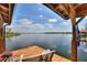 Boat dock with an upper level pontoon boat lift, bench, table and a flag at 29150 Beauclaire Dr, Tavares, FL 32778