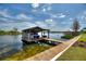 A covered boat dock features an upper level pontoon boat lift, a lower level deck, and a wooden walkway at 29150 Beauclaire Dr, Tavares, FL 32778