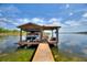 Covered boat dock featuring an upper level pontoon boat lift, a lower level deck, and a wooden walkway at 29150 Beauclaire Dr, Tavares, FL 32778