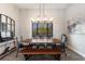 Modern dining room with long wood table, black chairs, and view to outside through black frame windows at 29150 Beauclaire Dr, Tavares, FL 32778