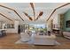 Open-concept living room with stone fireplace, wood beams, and seamless indoor-outdoor flow to pool and lake at 29150 Beauclaire Dr, Tavares, FL 32778