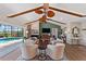 Spacious living room with fireplace, vaulted wood beam ceilings, modern furniture, and access to pool at 29150 Beauclaire Dr, Tavares, FL 32778