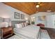 Cozy main bedroom with wood ceiling features a king bed, colorful artwork, and views to the bathroom at 29150 Beauclaire Dr, Tavares, FL 32778