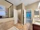 Bright bathroom featuring double sinks, glass shower, soaking tub, and neutral tile throughout at 30411 Gidran Ter, Mount Dora, FL 32757
