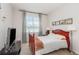 Cozy bedroom with a red-framed bed, soft curtains, and a collection of framed photos at 31 Abacus Ave, Ormond Beach, FL 32174