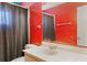Red bathroom with a single sink vanity, white toilet, and a shower/tub combo at 4366 Roanne Dr, Orlando, FL 32817