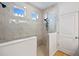 Bright shower with seamless glass enclosure, modern fixtures, white and beige marble-style tile and natural light at 4630 Cragmere Loop, Clermont, FL 34711