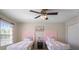 Charming bedroom featuring twin beds with pink accents and a ceiling fan for added comfort at 7299 Vista Park Blvd, Orlando, FL 32829