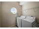 Functional laundry room featuring a washer, dryer, and a unique round window for natural light at 7299 Vista Park Blvd, Orlando, FL 32829