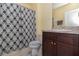 The bathroom features a shower with blue patterned curtains, a sink and tan cabinets at 9731 Pepper Tree Trl, Wildwood, FL 34785