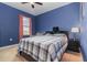This bedroom has blue walls, a ceiling fan, and a window that lets in natural light at 9731 Pepper Tree Trl, Wildwood, FL 34785