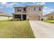 Two-story home featuring a two-car garage, well-maintained lawn, and inviting screened-in porch, enhancing its curb appeal at 9731 Pepper Tree Trl, Wildwood, FL 34785
