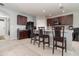 Open kitchen features dark wood cabinetry, granite countertops, a center island with bar seating, and modern appliances at 9731 Pepper Tree Trl, Wildwood, FL 34785