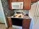 Kitchen with modern white microwave and white stove and dark countertops at 1062 Stillwater Ave, Deltona, FL 32725