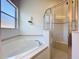 Bright and airy bathroom featuring a glass-enclosed shower and a soaking tub beneath a window at 120 Crepe Myrtle Dr, Groveland, FL 34736