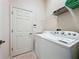 Well-organized laundry room featuring a washer and dryer and a door leading to another area at 120 Crepe Myrtle Dr, Groveland, FL 34736