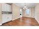 Dining area with hardwood flooring, white cabinets, backsplash, stainless appliances, and a modern chandelier at 14315 Crestavista Ave, Clermont, FL 34714