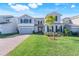 Charming two-story home with a well-manicured lawn, brick driveway, and lovely palm tree at 14315 Crestavista Ave, Clermont, FL 34714