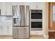 Stainless steel refrigerator and double ovens complemented by white cabinets and backsplash at 14315 Crestavista Ave, Clermont, FL 34714