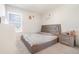 Bright bedroom features a large window, simple decor, and a neutral gray headboard with matching side table at 14418 Bayuk Way, Winter Garden, FL 34787