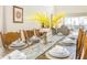 Dining room with wooden table set for a meal with yellow flower centerpiece and backyard view at 1555 Flange Dr, Davenport, FL 33896