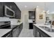 Galley kitchen featuring stainless steel appliances, white subway tile, and sleek dark cabinets at 1555 Flange Dr, Davenport, FL 33896