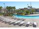 Outdoor pool area with lazy river, palm trees, lounge chairs, and bridge on a sunny day at 1555 Flange Dr, Davenport, FL 33896