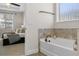 Bright bathroom featuring a soaking tub with diamond pattern tile accents and a view of the adjacent bedroom at 16089 Parkwyn St, Winter Garden, FL 34787