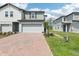 Charming townhome featuring a brick driveway, two-car garage, and neutral-toned siding under a bright, partly cloudy sky at 16450 Bird Of Paradise Ave, Clermont, FL 34714
