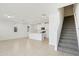 Open-plan living room featuring white kitchen, staircase, tile flooring, and plenty of natural light at 16450 Bird Of Paradise Ave, Clermont, FL 34714