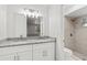 Bathroom featuring double vanity with granite top, framed mirror, and a tiled shower with a shower head at 1811 Oakgrove Ave, Deltona, FL 32725