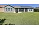 Rear view shows a well-maintained lawn, screened lanai, and solar panels, offering energy efficiency at 228 Bayou Bend Rd, Groveland, FL 34736