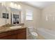 Bright bathroom with a large mirror, granite-topped vanity, tiled shower-tub, and a toilet near the window at 2319 Grantham Ave, Davenport, FL 33837