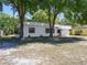 A well-kept single-story home with mature trees, a white exterior and a neat front yard on a sunny day at 2429 Yale Ave, Sanford, FL 32771