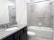 Bathroom featuring granite countertop vanity, dark cabinets and tiled shower and bath with safety bars at 398 Citrus Isle Loop, Davenport, FL 33837