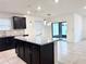 Modern kitchen features an island with granite countertops, dark cabinetry, and stainless steel appliances at 398 Citrus Isle Loop, Davenport, FL 33837