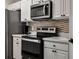 Close-up of the kitchen with white cabinets, stainless steel microwave and oven, and a decorative backsplash at 581 Brantley Terrace Way # 209, Altamonte Springs, FL 32714