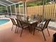 Screened patio with a glass-topped table, chairs, and view of the wooded backyard and pool at 6037 Hickory Grove Ln, Port Orange, FL 32128
