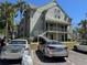 Two story building with light green exterior, gray metal staircases, with mature palm trees on a sunny day at 6142 Westgate Dr # 304, Orlando, FL 32835