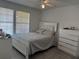 Bright main bedroom featuring light gray wood floors, a ceiling fan, and a large bed with a white headboard at 6142 Westgate Dr # 304, Orlando, FL 32835