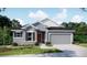 Charming single-story home featuring a two-car garage, neutral paint, dark shutters, and manicured landscaping at 6611 Lullaby Ln, Mascotte, FL 34753